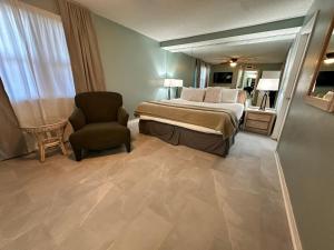 沃尔顿堡滩Nautilus 1702 Gulf Front Large 2 Bedroom Penthouse 7th Floor的一间卧室配有一张床、一把椅子和镜子