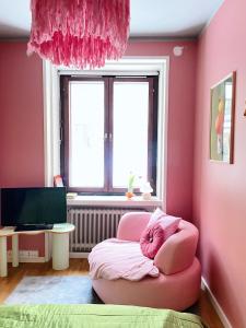 赫尔辛基Värikäs koti lähellä keskustaa的粉红色的房间,配有粉红色的椅子和窗户