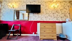威灵堡哥伦比亚酒店的一间设有红色墙壁、电视和梳妆台的房间