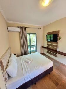 瓜鲁雅Vila Jabutis的一间卧室配有一张大床和电视