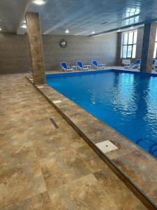 萨克德佐尔镇Alvina apartment Tsaghkadzor的大楼内带蓝色椅子的大型游泳池