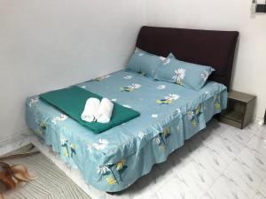 Pasir MasAINUL HOMESTAY的一张带蓝色棉被的床和两条毛巾