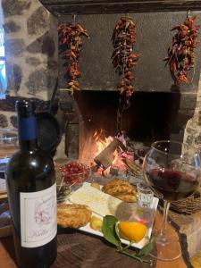 BulqizëKulla Hupi Agriturism的一瓶葡萄酒、一盘食物和一个壁炉