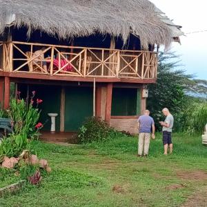 安博塞利KILIMANJARO COTTAGES AMBOSELI的两个人站在房子前面