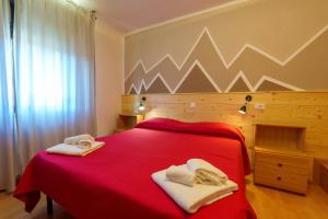 阿尔塔泰尔梅Hotel Park Oasi的一间卧室配有红色的床和毛巾