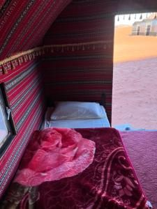 瓦迪拉姆哈立德营地酒店的帐篷内的一张床位,上面有一条红毯