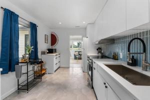 盖恩斯维尔Smart Bungalow: 10-min to UF, Central Location的厨房配有白色的柜台和蓝色的窗帘