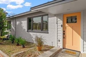 盖恩斯维尔Smart Bungalow: 10-min to UF, Central Location的一座白色的房子,有橙色的门和植物