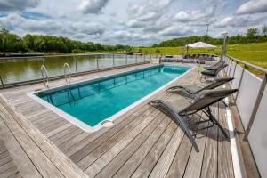 伊特尔Tabor 67 Luxury Houseboat的木甲板,设有游泳池和码头上的椅子