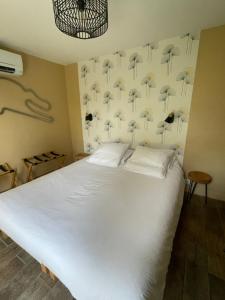 勒芒Cabane du Circuit的卧室配有白色的床和带遮阳伞的墙壁。