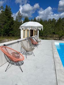 SliteVilla VitvikenA in Gotland Pool的游泳池旁的3把椅子和凉亭