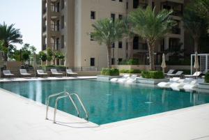 迪拜Spectacular 2BR Apartment Full BurjAlArab View的一座游泳池,位于酒店,设有椅子和棕榈树