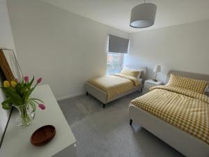 牛津Modern and Comfortable Flat with private parking的一间卧室设有两张床和一张花瓶桌子。