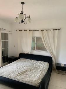 塞罗阿苏尔Cabaña Holly Water的一间卧室配有一张带吊灯和窗户的床。