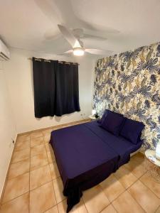 法兰西堡Le Toucan Tropical, F2 bis emplacement central的一间卧室配有紫色的床和吊扇