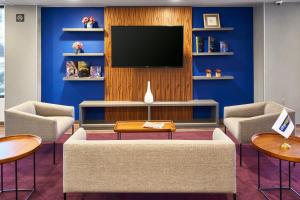 托卢卡都市快捷托卢卡酒店的客厅配有电视和蓝色的墙壁