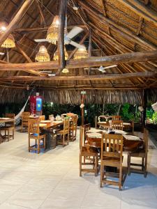 埃尔扎伊诺Ecohabs Bamboo Parque Tayrona - Dentro del PNN Tayrona的餐厅设有木桌、椅子和吊灯。