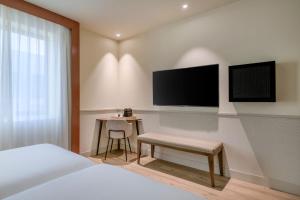 马德里巴斯克AC酒店 - 万豪时尚酒店 的一间卧室配有一张床、一张书桌和一台电视。
