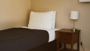 玛拉豪The Barn Cabins & Camp的一张带白色枕头的床和一张带台灯的桌子