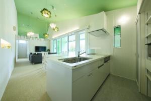 郡上市绿园度假屋酒店的一间带水槽的白色厨房和一个客厅