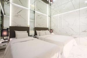 首尔Hotel Star Premier Yeoksam的配有白色大理石墙壁的客房内的两张床