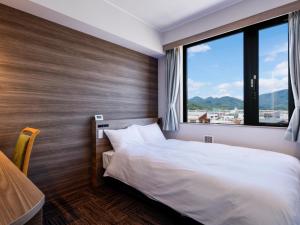 田边市ホテル紀伊田辺的一间卧室设有一张床和一个大窗户