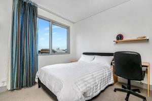 悉尼CBD Chinese Gardens Views, Modern 2BR Apt SX339的卧室配有床、椅子和窗户。