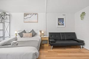 悉尼Premier Leichhardt Stayz的一间卧室配有两张床和一张黑色沙发