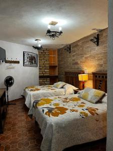 瓦斯卡坎波Hotel Huasca Terrazza的一间卧室设有两张床和砖墙