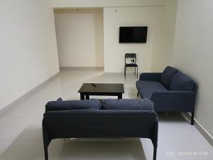 乌杜皮City Center Apartments的客厅配有2张蓝色的沙发和1张桌子