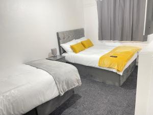 BraunstoneHometel Hidden Gem Large Comfy Home Can Sleep 13的卧室内的两张床和黄色枕头