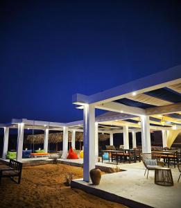 Al QābilSAMA Al Areesh Camp的海滩上的一个凉亭,晚上配有桌椅