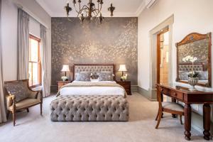 比勒陀利亚蒙特城堡酒店的卧室配有1张床、1张桌子和1把椅子