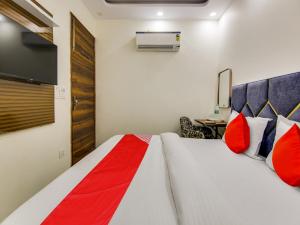 新德里OYO AR Residency的一间卧室配有一张带红色枕头的床和一台电视。