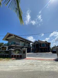 哥打巴鲁Airport Kota Bharu Homestay & Riverview Inn的街道前有棕榈树的房子