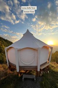 KhuloGlamping Tago的坐在草地上的帐篷,背面是日落