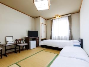 函馆Seoul Garden Hotel的客房设有两张床、一张桌子和一台电视。