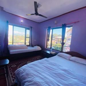 班迪普尔Himchuli Guest House的一间卧室配有两张床和吊扇