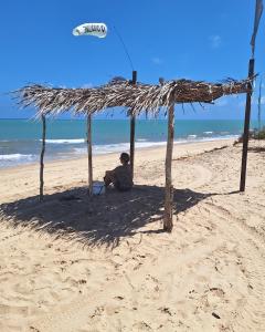 托鲁斯Sol & Vento Chalés的坐在海滩小屋下的人