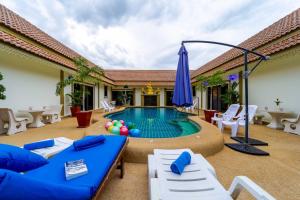 邦萨雷Siam Court Hotel and Resort的庭院中间的游泳池,配有椅子和遮阳伞