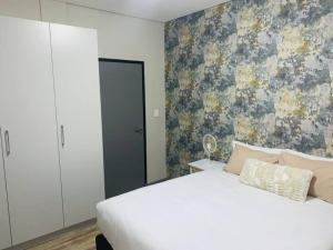 温特和克DMN City Merensky Apartment的卧室配有白色的床和花卉壁纸