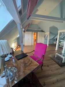 希尔德斯海姆Hotel Stadtresidenz的配有桌子和粉红色椅子的房间