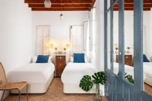 塞维利亚Magno Apartments Vírgenes Luxury House的一间设有两张床、椅子和门的房间