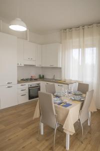 卡斯泰莱门多La Casa dei Racconti的一间带桌椅的厨房和一间带白色橱柜的厨房