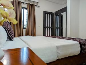 科托努Les Ombrelles Appart'Hotel的卧室配有白色的床,铺有木地板