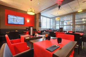 朗吉斯假日度假奥利酒店的餐厅设有红色的桌椅和电视。