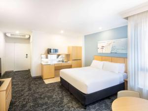 悉尼Mercure Sydney Manly Warringah的酒店客房带一张床和一个厨房