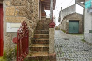 戈韦阿Rustic Getaway in Guarda的一座古老的石头建筑,设有红色的栅栏和楼梯