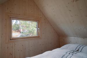 赫尔辛基Majamaja Helsinki off-grid retreat的木制客房的一张床位,设有窗户