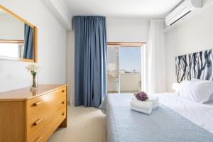 珀彻斯Casa Azul 3 - Senhora da Rocha, Algarve的一间卧室配有一张床、一个梳妆台和一扇窗户。